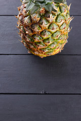 Pineapple on wooden boards, pineapple with leaves on black background, tropical fruit with copy space, blank for designer, vegetarian food, fruit for salad preparation, art