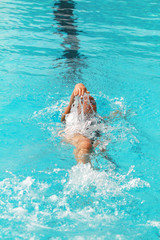 Swimmer swims backstroke or back crawl in a swimming pool for competition or race