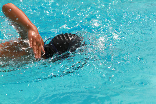 Young swimmer with black cap swim free style or forward crawl in a swimming pool for competition or race