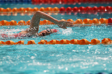 Asian girl with red cap swim free style or forward crawl in swimming pool for competition or race