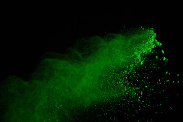 Freeze motion of green powder explosions isolated on black background. Green dust explosive on dark background. Colored clouds splash.