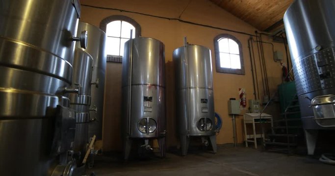 Wine production industry, detail of small metal tanks. Slow traveling, panning and rotating at tanks room at floor level. Mendoza, Argentina. 