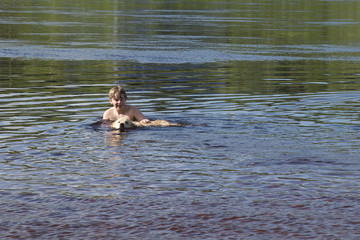 dog and boy swimming in the river
