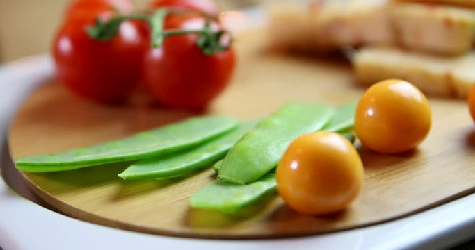 Yellow cheese with fresh vegetables. Tomatoes. Pease. on orange background.