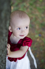 A child is standing and holding on to a tree.