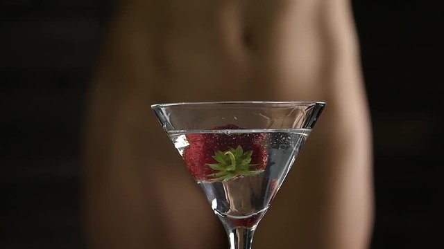 sexy young woman in a white panties prepares a cocktail with strawberry in a dark. close-up buttocks and hip. slow motion