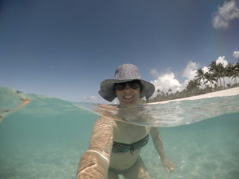 Selfie of a smiling middle aged woman in hat and shades in sea at Matautu, Lefaga, Upolu Island, Samoa, South Pacific