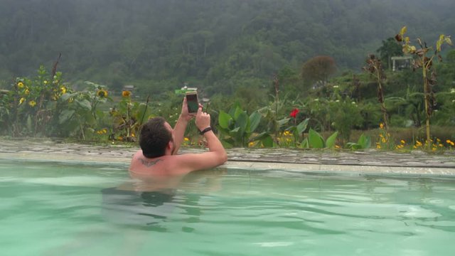 A man makes selfi in a pool with thermal water