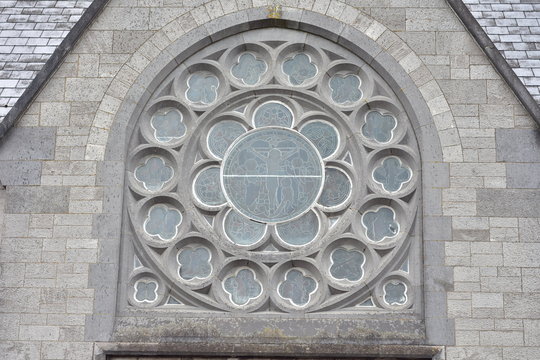 Round stained glass windows on stone early English style church in Ireland.