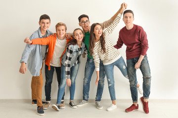 Group of cute teenagers standing near white wall
