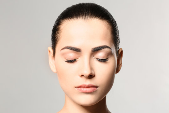 Naklejki Young woman with permanent eyebrows makeup on grey background