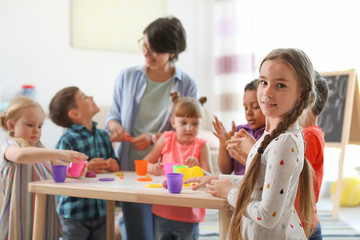 Young woman playing with little children indoors