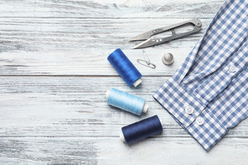 Flat lay composition with accessories for tailoring on wooden table