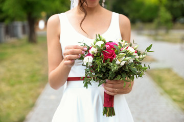 Woman in wedding gown with beautiful bridal bouquet outdoors, closeup