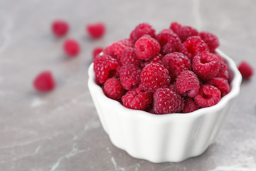 Bowl with ripe aromatic raspberries on table