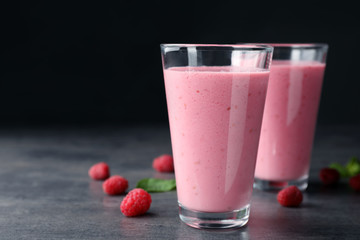 Delicious smoothie in glasses and fresh raspberries on table