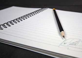 Close up black wooden pencil lying on a spiral notebook.