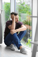Lonely depressed man near window at home