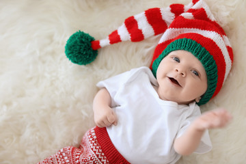 Adorable baby in Christmas hat on fuzzy rug