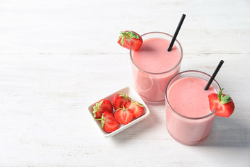 Glasses with tasty strawberry smoothie on table