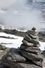 Pyramid of large stones on top of a high mountain above the clouds