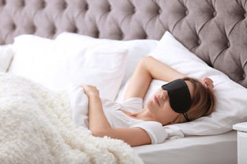 Young beautiful woman with mask sleeping in bed at home. Early morning