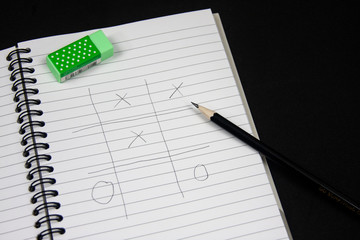 Naklejka premium Playing Tic Tac Toe on the note book.