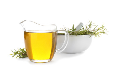 Jug of oil and fresh herb in mortar on white background