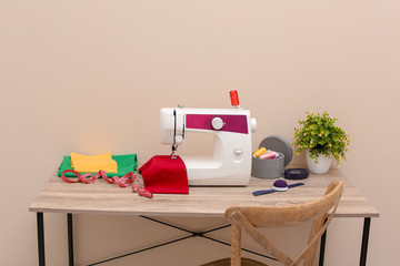 Modern sewing machine on table against light background