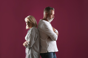 Upset mature couple on color background. Relationship problems