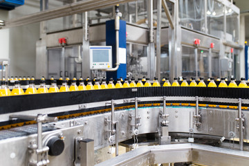 Industrial factory indoors and machinery. Robotic factory line for processing and bottling of soda and orange juice bottles