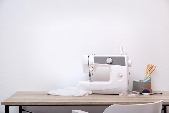 Sewing machine on table against light background
