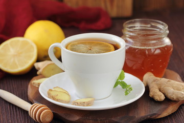Cup of ginger tea with honey and lemon on wooden table