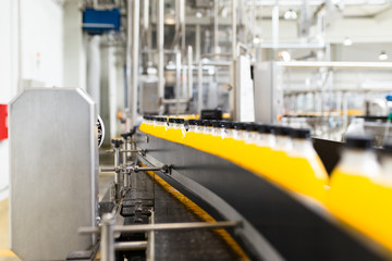 Industrial factory indoors and machinery. Robotic factory line for processing and bottling of soda and orange juice bottles