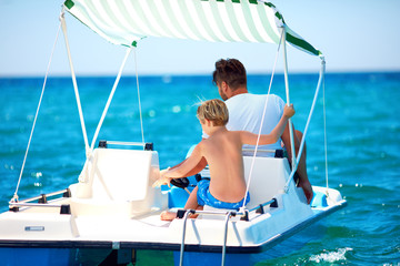happy family, father and son enjoy sea adventure on watercraft catamaran at summer vacation