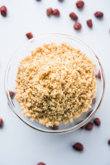 Crushed peanuts or mungfali powder with whole and roasted groundnut. Served in a bowl over moody background. Selective focus