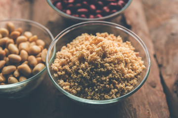 Crushed peanuts or mungfali powder with whole and roasted groundnut. Served in a bowl over moody background. Selective focus