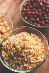 Crushed peanuts or mungfali powder with whole and roasted groundnut. Served in a bowl over moody background. Selective focus