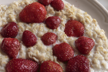 Hot oatmeal porridge with cream and fresh strawberries. Healthy breakfast concepts.