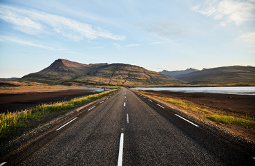 The road to the horizon in Iceland. Typical Iceland landscape with road and mountains. Summer time.
