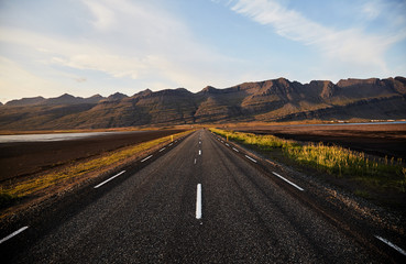 The road to the horizon in Iceland. Typical Iceland landscape with road and mountains. Summer time.