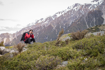 a traveller, photographer man taking photo on the mountain, snow mountain in background