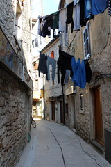 Clothes drying on ropes between old stone buildings in Mediterranean street at afternoon