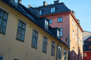 Fototapeta na wymiar Windows and roofs and walls, shadows and morning rising sun in Old city in Stockholm, Sweden. 