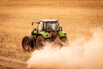 Mulching tractor after rapeseed harvest among the dust