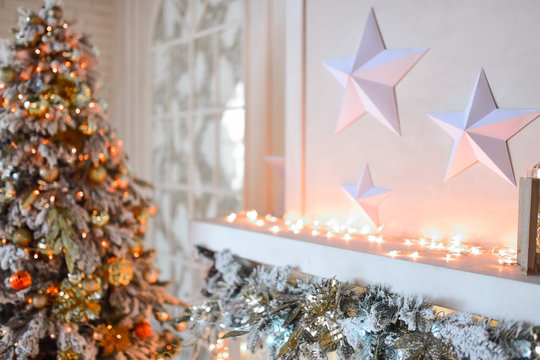 White Fireplace Decorated With Yellow Garland And Christmas Tree Standing By It