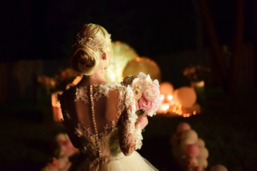 Bride walks on the evening backyard holding with a bouquet