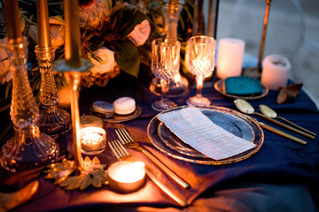 Fototapeta na wymiar Menu card lies on a blue plate surrounded with golden dinner set