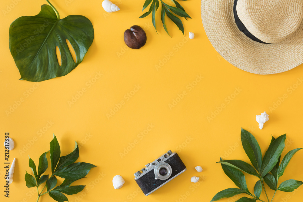 Wall mural Flat lay design of yellow background with laptop, photo camera, green palm tropical leaf and flowers, top view. Summer background, vacations and holidays, trip and travel planning concept