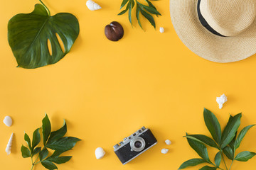 Flat lay design of yellow background with laptop, photo camera, green palm tropical leaf and flowers, top view. Summer background, vacations and holidays, trip and travel planning concept - Powered by Adobe